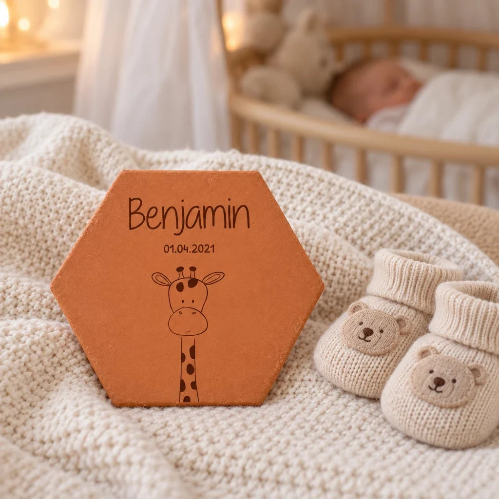 Giraffe terracotta tile on a knitted blanket with baby booties.