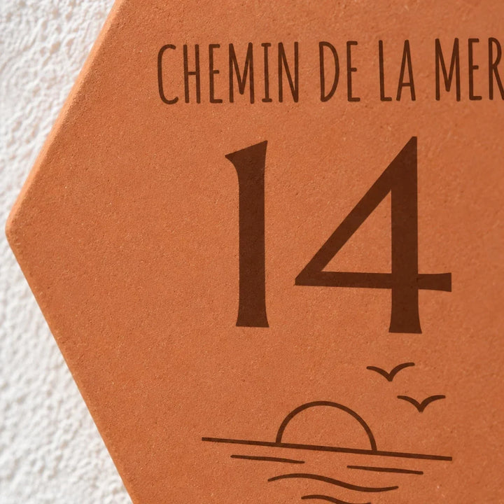 Gros plan sur le numéro 14, le soleil et les vagues gravés sur la plaque.