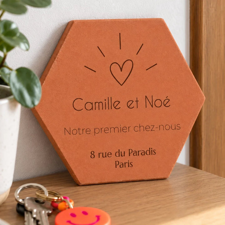 Tomette personnalisée « Notre premier chez-nous », Camille et Noé, cœur et adresse gravés, vue de près sur la console, avec les prénoms et l’adresse gravés visibles.