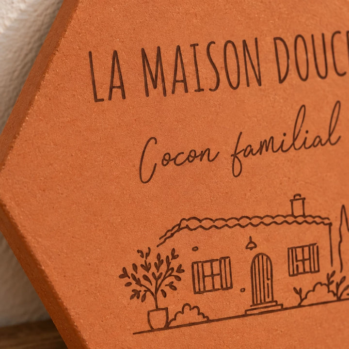 Gros plan sur les mots Cocon familial et la maison avec arbres gravés.