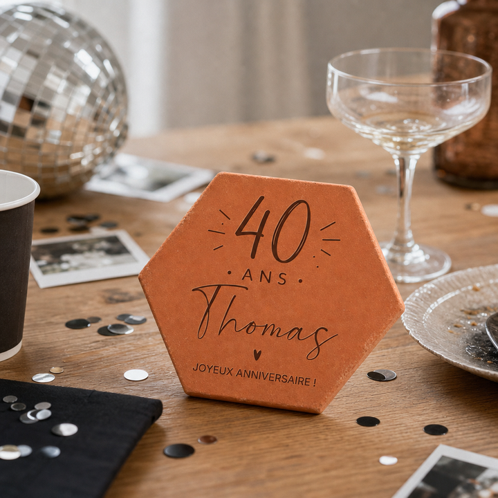 Tomette « 40 ans » sur une table avec photos, confettis et boule à facettes.