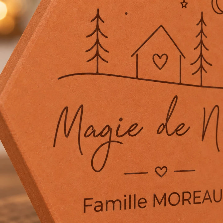 Gros plan sur la maison à cœur, les sapins et le nom Famille Moreau gravés.