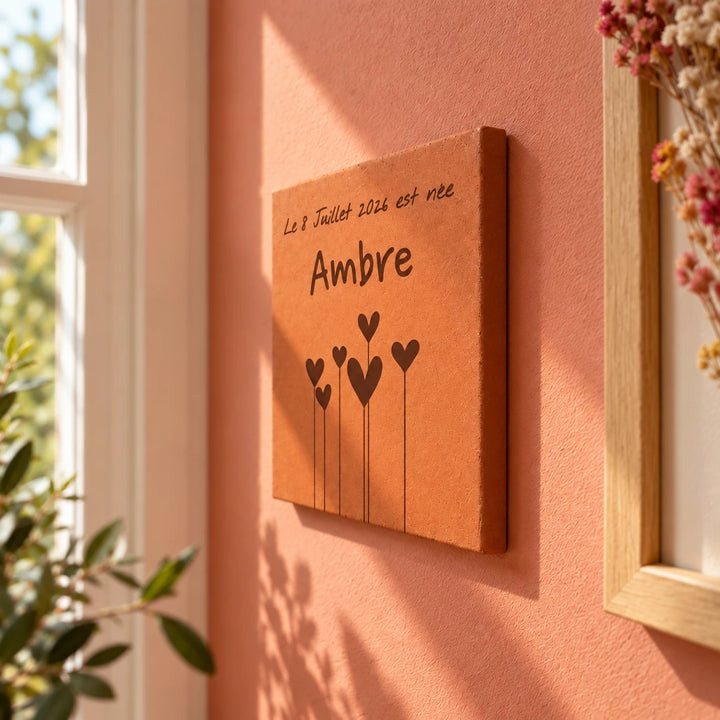 Tomette décorative Fleurs en coeur - Naissance, accrochée au mur près d’une fenêtre — vue de profil