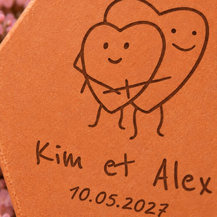 Carreau décoratif Coeurs amoureux en terre cuite, posé sur des fleurs roses pastel. — vue rapprochée du motif