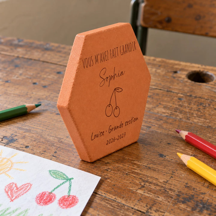 Tomette personnalisée Merci maîtresse, motif cerises, sur vieux bureau d’écolier avec dessin et crayons — vue de profil