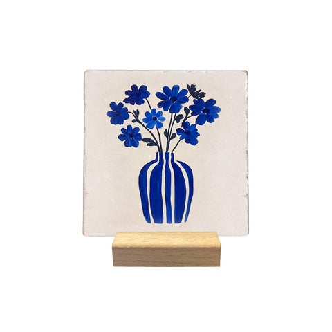 Blue Vase and Flowers decorative tile, with a blue bouquet on a light background, displayed on a small wooden stand against a white background.
