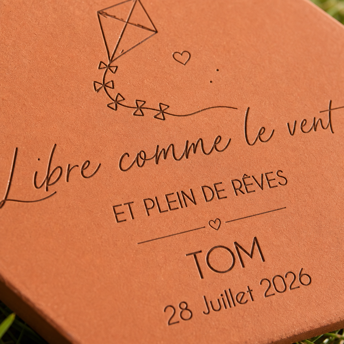 Détail du cerf-volant, du prénom Tom et de la date gravés sur la tomette.