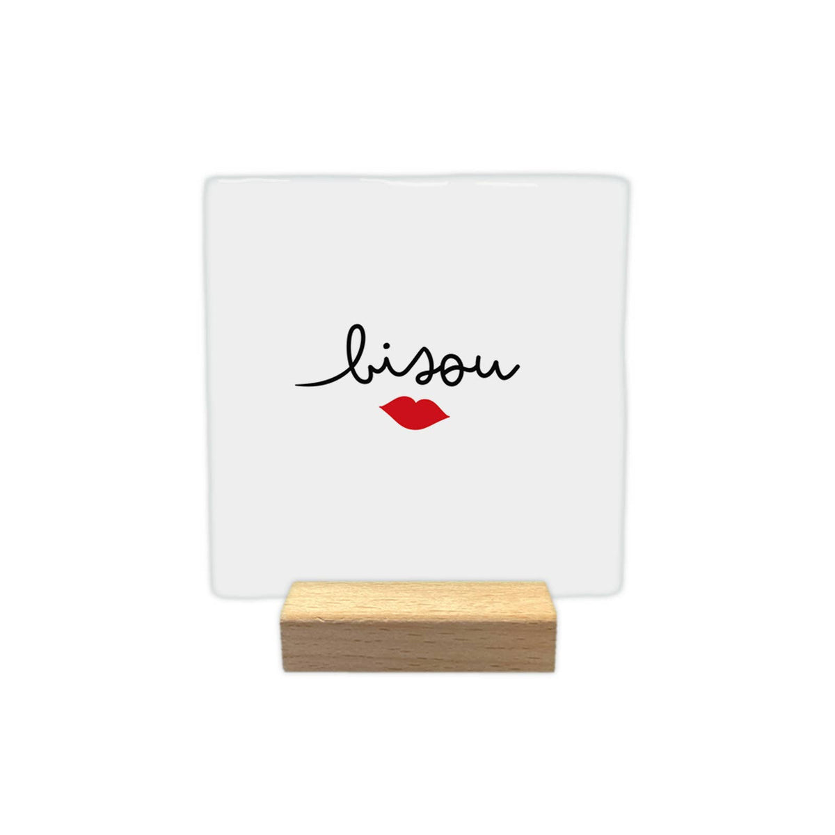 Carreau décoratif blanc « bisou » avec une bouche rouge, présenté sur un petit support en bois sur fond blanc.