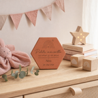 Tomette de naissance personnalisée Alba, arc-en-ciel et « Petite merveille » gravés, sur une commode près d’une étoile lumineuse, de livres et de cubes.