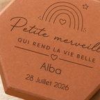 Gros plan sur l’arc-en-ciel, le prénom Alba et la date gravés sur la tomette.