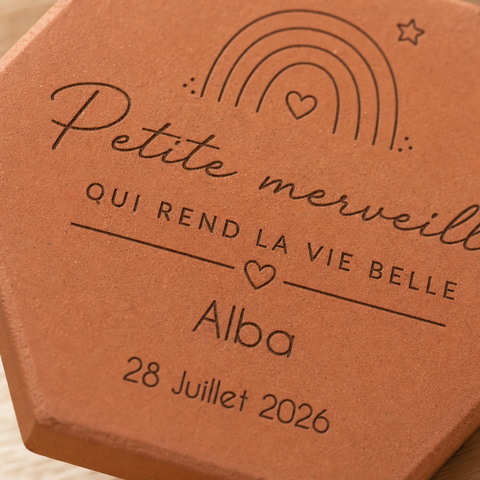 Gros plan sur l’arc-en-ciel, le prénom Alba et la date gravés sur la tomette.