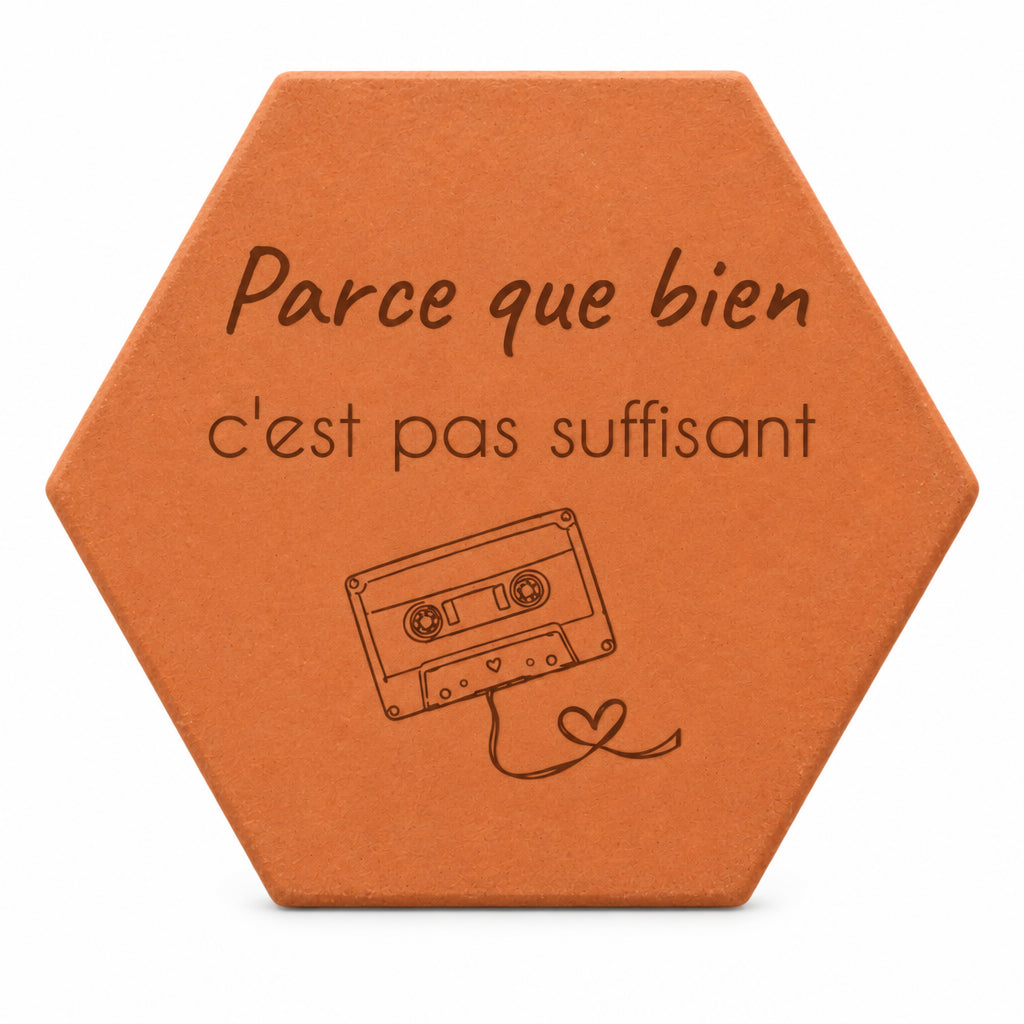 Hexagonal terracotta tile engraved with “Parce que bien c'est pas suffisant” — white background.