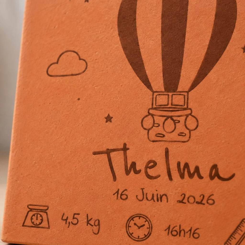 Détail du carreau faire-part : montgolfière, prénom Thelma et date gravés.