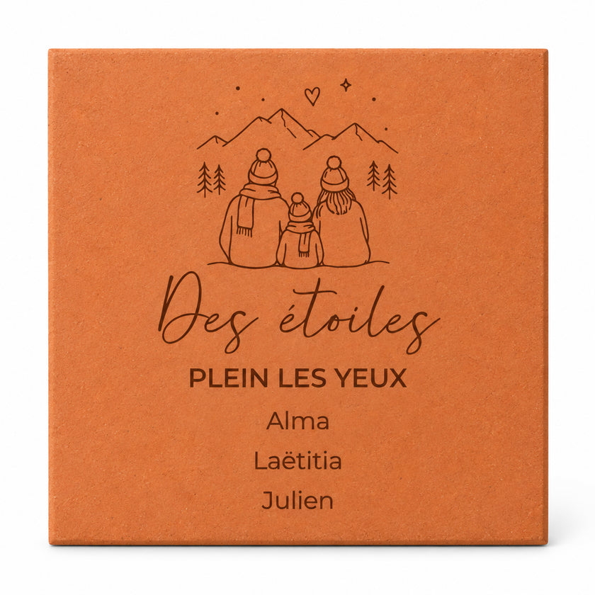 Personalised tile engraved with “Des étoiles plein les yeux”, a family in the mountains and three first names, on a white background.