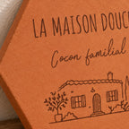 Gros plan sur les mots Cocon familial et la maison avec arbres gravés.