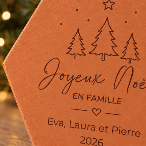 Détail des sapins, du cœur et des prénoms Eva, Laura et Pierre gravés sur la tomette de Noël.