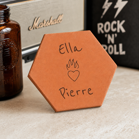 Tomette de couple personnalisée Ella et Pierre, cœur en flammes gravé, devant une enceinte et une décoration Rock’n’Roll.