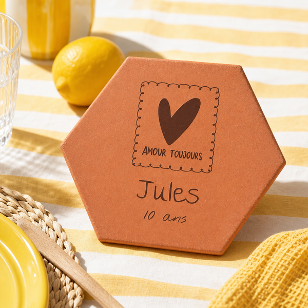 Cadeau de naissance : tomette hexagonale personnalisée en terre cuite de Salernes gravée au laser sur table d'été jaune.
