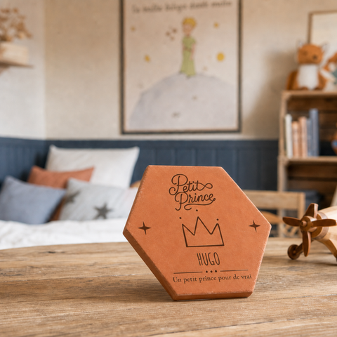 Tomette personnalisée « Petit Prince », Hugo et couronne gravés, vue de biais sur une table en bois près d’un jouet animal.