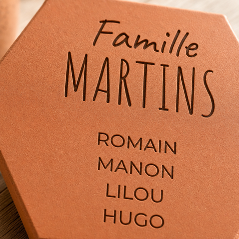 Gros plan sur Famille Martins et les prénoms Romain, Manon, Lilou et Hugo gravés.