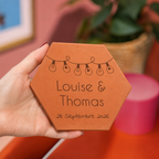 Mariage : tomette hexagonale personnalisée, terre cuite de Salernes gravée au laser, tenue dans une main de femme.