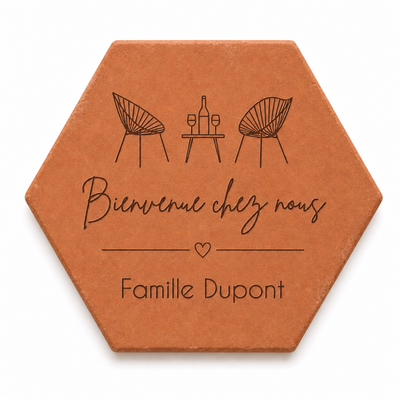 Cadeau crémaillère avec tomette hexagonale personnalisée, terre cuite de Salernes gravée au laser, terrasse et maison provençale floutées.