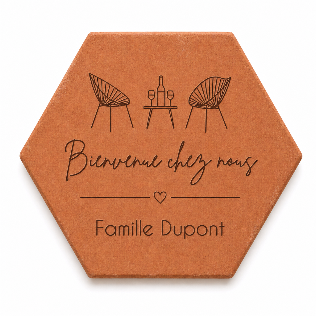 Cadeau crémaillère avec tomette hexagonale personnalisée, terre cuite de Salernes gravée au laser, terrasse et maison provençale floutées.