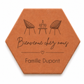 Cadeau crémaillère avec tomette hexagonale personnalisée, terre cuite de Salernes gravée au laser, terrasse et maison provençale floutées.