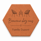 Cadeau crémaillère avec tomette hexagonale personnalisée, terre cuite de Salernes gravée au laser, terrasse et maison provençale floutées.