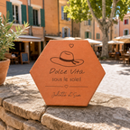 Cadeau souvenir de Provence, tomette hexagonale personnalisée en terre cuite de Salernes gravée au laser, en fond une place provençale.