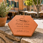 Cadeau souvenir de Provence, tomette hexagonale personnalisée en terre cuite de Salernes gravée au laser, en fond une place provençale.