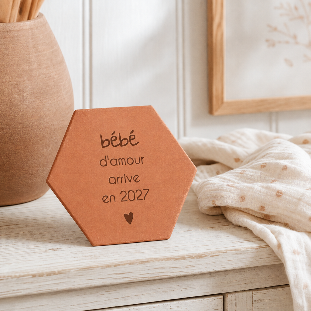 Annonce naissance : tomette hexagonale personnalisée, terre cuite de Salernes gravée au laser, en mains lors d'une fête de famille.