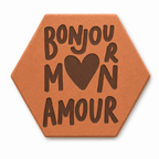 Tomette gravée « Bonjour mon amour » en grandes lettres avec cœur, sur fond blanc.