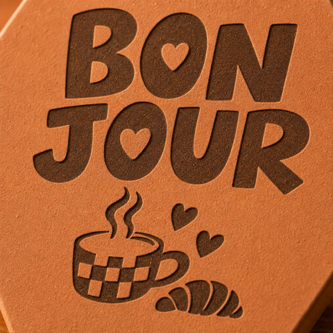 Gros plan sur Bonjour, la tasse fumante à carreaux, le croissant et les cœurs gravés.