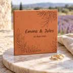 Carreau de mariage personnalisé Emma et Jules, date et feuillages gravés, posé près de deux alliances devant un champ de lavande.