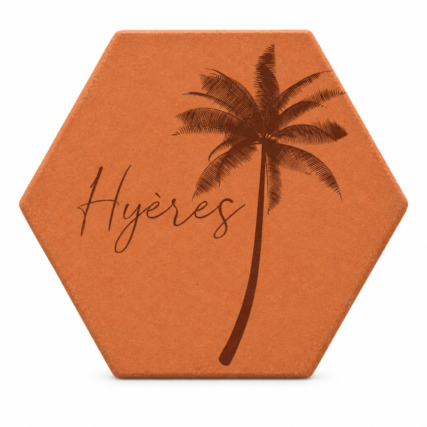 Terracotta tile with an engraved palm tree and destination city, in a postcard design — white background.
