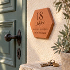 Personalised house plaque engraved with “18 rue des Oliviers”, “Aix-en-Provence” and a branch, viewed from the side beside the green door, above a bunch of keys.