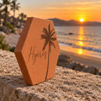 Tomette souvenir personnalisée « Hyères » avec palmier gravé, vue de côté sur un muret au bord de la mer.