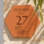 Personalised “Quai des Embruns, Cassis” house plaque, engraved with the number 27 and a small boat, shown close up on the wall, with the engraved boat and houses visible.