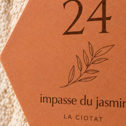 Gros plan sur le numéro 24, le rameau et l’adresse gravés sur la plaque.