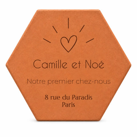 Cadeau de crémaillère pour un couple : tomette « Notre premier chez-nous », Camille et Noé, cœur et adresse gravés, sur fond blanc.