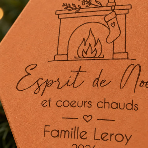 Gros plan sur la cheminée, la chaussette suspendue et le nom Famille Leroy gravés.