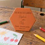 Tomette personnalisée Merci maîtresse, motif cerises, sur vieux bureau d’écolier avec dessin et crayons — vue en situation