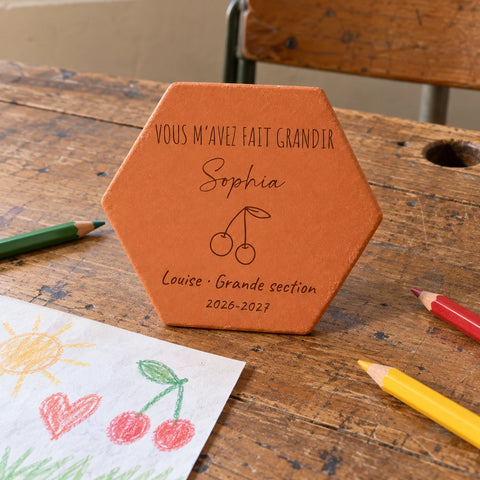 Tomette personnalisée Merci maîtresse, motif cerises, sur vieux bureau d’écolier avec dessin et crayons — vue en situation