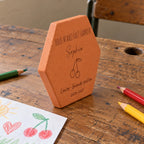Tomette personnalisée Merci maîtresse, motif cerises, sur vieux bureau d’écolier avec dessin et crayons — vue de profil